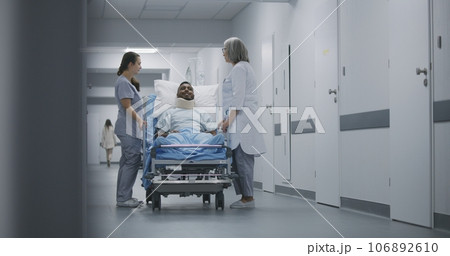 Medic and nurse walk down the clinic corridor with patient on gurney 106892610