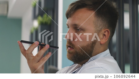 Portrait of male doctor talking by phone, recording voice message 106892644