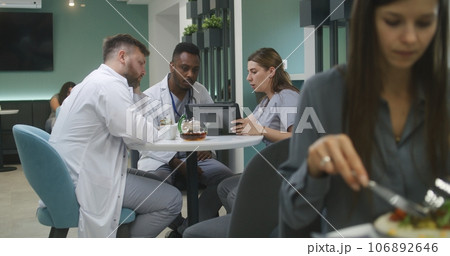 Multiethnic doctors sit in clinic cafe, use laptop 106892646
