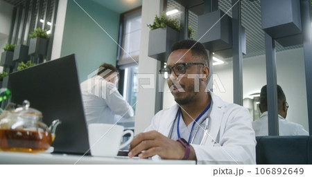 African American doctor uses laptop in modern clinic cafe 106892649