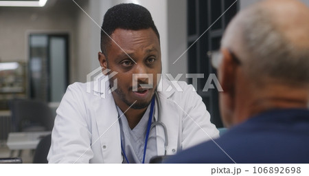 African American doctor discusses treatment with elderly patient in clinic cafe African American doctor discusses treatment with elderly patient in clinic cafe 106892698