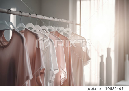 Beige and white clothes hanging on a rack Beige and white clothes hanging on a rack 106894054