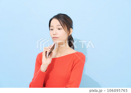 スマホを持って悩む表情の女性 106895765