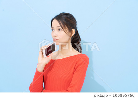 スマホを持って悩む表情の女性 106895766