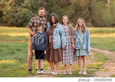 A large friendly family walks in a field in the summer 106898460