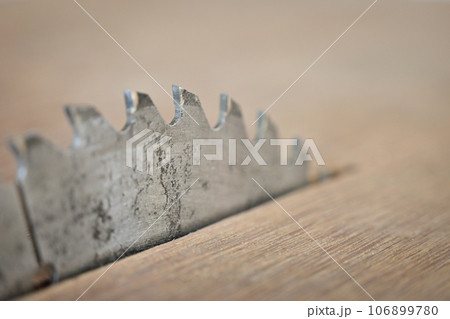 sharp metal saw on wood plank texture background, construction machine 106899780