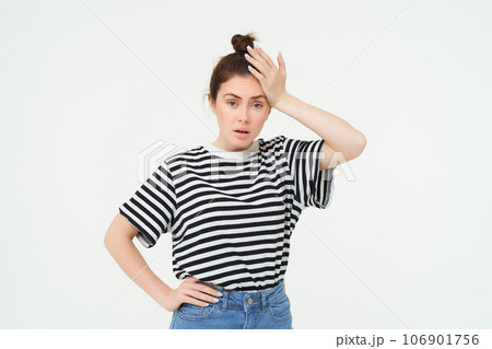 Shocked woman, slaps her forehead, holds hand on head and looks startled, concerned re something bad, terrible situation, standing over white background 106901756