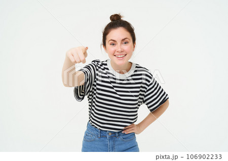 Image of stylish young woman, pointing finger at camera, inviting you, standing over white background 106902233
