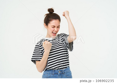 Portrait of happy woman winning, celebrating victory, rooting for team, triumphing, standing over white background Portrait of happy woman winning, celebrating victory, rooting for team, triumphing, standing over white background 106902235