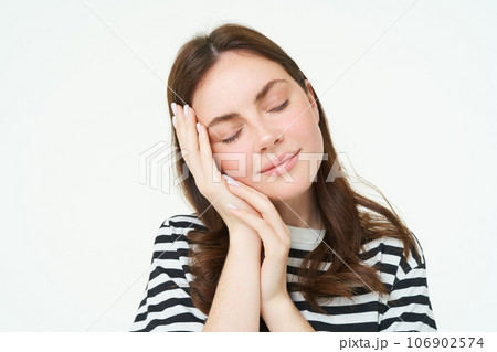 Close up portrait of tender, smiling young woman, closes her eyes and touches her palm, sleeping on her hand, isolated on white background Close up portrait of tender, smiling young woman, closes her eyes and touches her palm, sleeping on her hand, isolated on white background 106902574