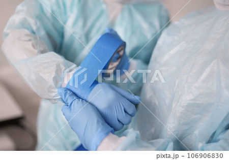 Nurse gluing tape on sleeve of surgical suit closeup Nurse gluing tape on sleeve of surgical suit closeup 106906830