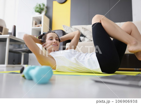 Young woman toned abs on rug at home while watching video guide on laptop 106906938