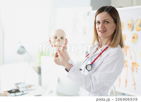 Female doctor teacher holding human skull closeup 106906939
