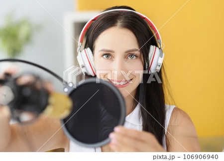 Portrait of smiling woman in headphones in front of microphone in studio 106906940