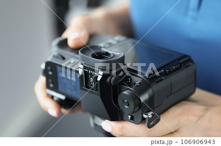 Black professional camera in female hands closeup 106906943