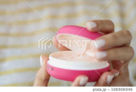 Hands of beautiful well-groomed woman with pink jar of cream 106906946