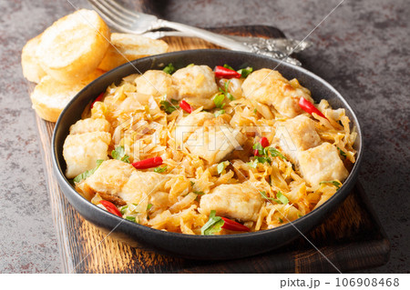 Stewed white cabbage with sea fish fillet, onion and chili pepper close-up in a plate served with toast. horizontal 106908468