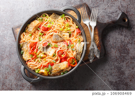 Main course spaghetti with white fish fillet, peppers, onions, green peas and tomato sauce close-up in a frying pan. Horizontal top view Main course spaghetti with white fish fillet, peppers, onions, green peas and tomato sauce close-up in a frying pan. Horizontal top view 106908469