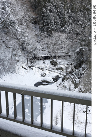 袋田の滝近くにある、雪に覆われた真冬の渓谷に掛かる吊り橋 106909490