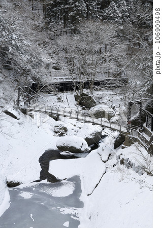 袋田の滝近くにある、雪に覆われた真冬の渓谷に掛かる吊り橋 106909498