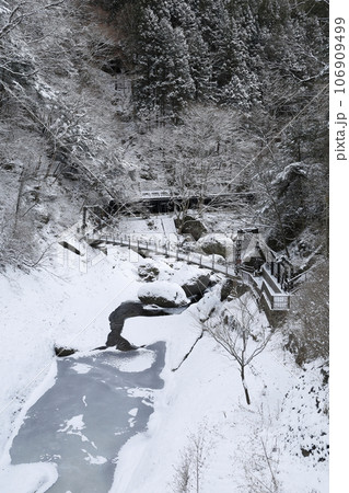 袋田の滝近くにある、雪に覆われた真冬の渓谷に掛かる吊り橋 106909499