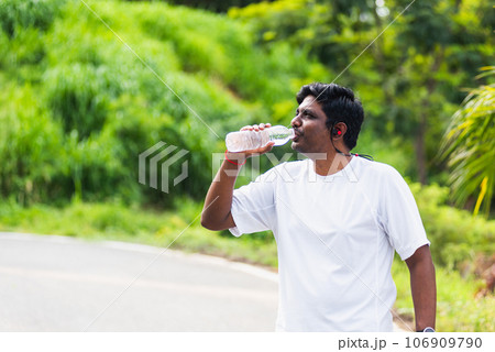 Close up Asian young sport runner black man wear athlete headphones he drinking water from a bottle after running at the outdoor street health park, healthy exercise workout concept Close up Asian young sport runner black man wear athlete headphones he drinking water from a bottle after running at the outdoor street health park, healthy exercise workout concept 106909790