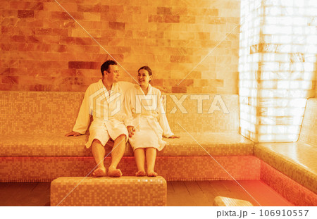 Young married couple in white bathrobes sits and relaxes in the salt room. 106910557