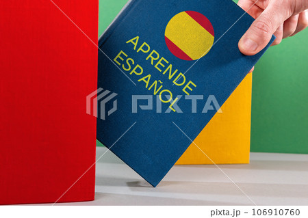 A male's hand holds an blue Spanish textbook. Close-up. Spanish Language Day Concept 106910760
