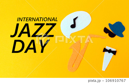 Silhouette of a musician with a saxophone from which melodie flew out, on a yellow background, cutted out of felt. Flat lay. International Jazz Day Silhouette of a musician with a saxophone from which melodie flew out, on a yellow background, cutted out of felt. Flat lay. International Jazz Day 106910767
