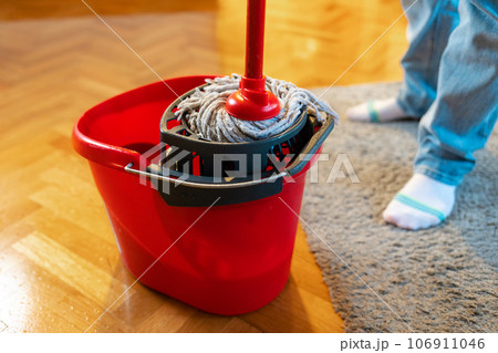 Cleaning person dips mop into bucket. Close-up of the legs, top view. Chores and washing 106911046