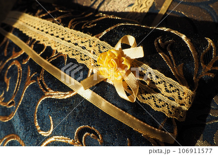 A beautiful yellow-orange lace artificial flower sewn onto a decorative cushion satin fabric. Blue dense braid with thin polyester lace. Decoration of decorative pillowcases. Women's needlework 106911577