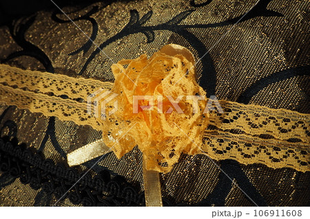 A beautiful yellow-orange lace artificial flower sewn onto a decorative cushion satin fabric. Blue dense braid with thin polyester lace. Decoration of decorative pillowcases. Women's needlework 106911608
