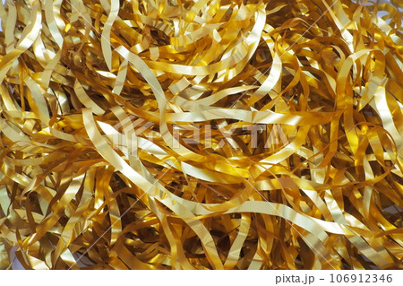 Tinsel-rain of golden color. New Year and Christmas decorations for the Christmas tree, interior or party room. Weaving threads of golden foil. Festive beautiful shiny background. Tinsel close-up 106912346