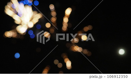 New Year's bokeh fireworks. Multicolored defocused sparks on the black night sky. Black background with abstract circles. A beautiful glowing explosion with yellow, blue and brown lights flying out New Year's bokeh fireworks. Multicolored defocused sparks on the black night sky. Black background with abstract circles. A beautiful glowing explosion with yellow, blue and brown lights flying out 106912350