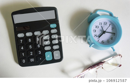 On a white background calculator, glasses and alarm clock On a white background calculator, glasses and alarm clock 106912587