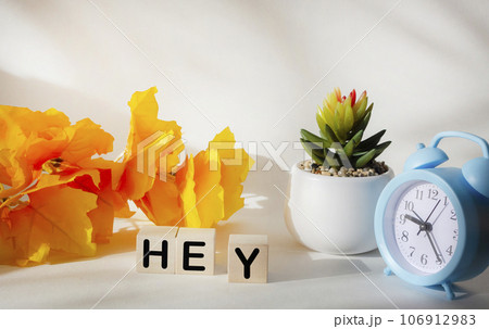 Word hey made from wooden blocks on white background with yellow foliage and clock Word hey made from wooden blocks on white background with yellow foliage and clock 106912983