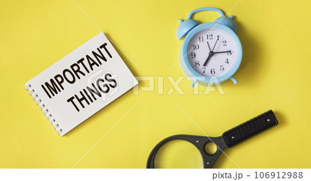 Text Important things on a notepad on a yellow background with a magnifying glass and a clock. 106912988