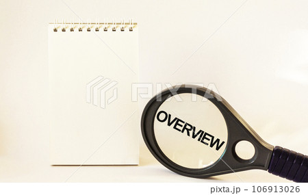 Overview, the text is written on a magnifying glass next to a notepad. White background Overview, the text is written on a magnifying glass next to a notepad. White background 106913026