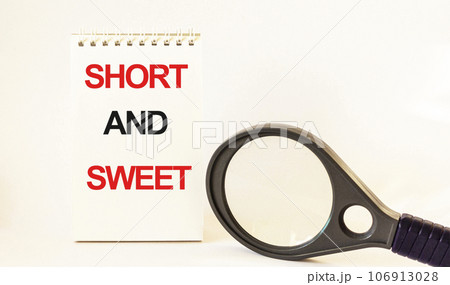 Short and sweet, written on notepad and white background. Near a magnifying glass 106913028