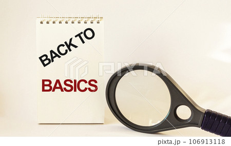 BACK TO BASIC, text written on notepad and white background, near a magnifying glass 106913118