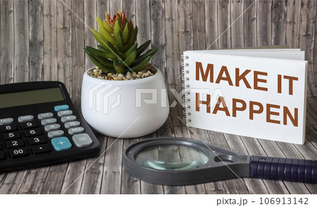 Make it possible, the phrase is written on a notebook and a wooden table. Motivational slogan. 106913142