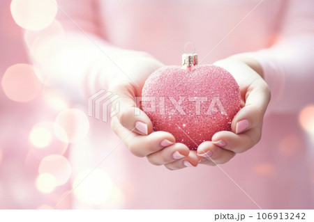Christmas heart shaped decoration in woman's hands on pink background 106913242