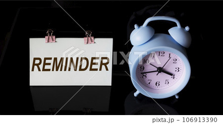 Reminder, text on sticker. There is an alarm clock on a black background 106913390