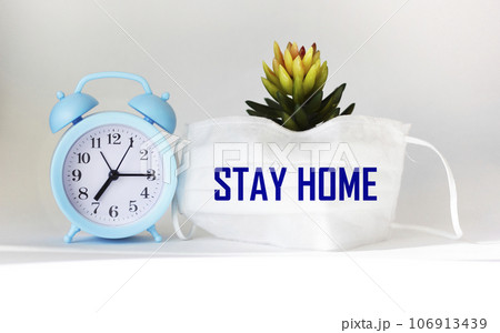 Stay at home save lives phrases on a medical mask on a white background with a clock  106913439