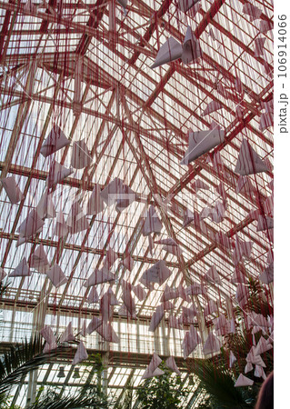 ガラスハウスの中に吊り下げられた沢山の赤い糸と紙でできたオブジェ　ロンドン郊外のキューガーデンにて 106914066