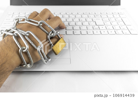 鎖の巻かれた手とノートパソコンのキーボード。依存症のイメージ 106914439