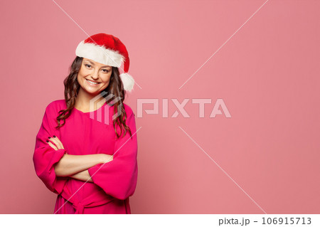 Beautiful positive Christmas woman Santa smiling and looking at camera on pink background 106915713
