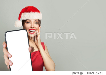 Christmas surprised woman in Santa hat holding smartphone with empty blank display screen Christmas surprised woman in Santa hat holding smartphone with empty blank display screen 106915740