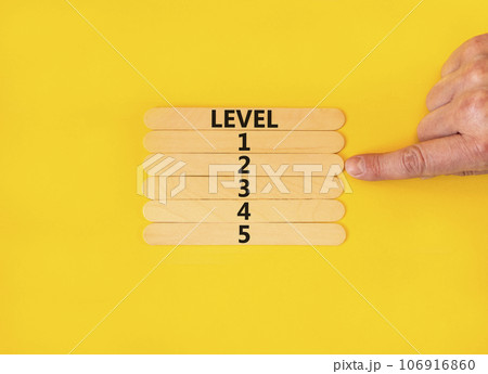 Time to level 2 symbol. Concept word Level 1 2 3 4 5 on wooden sticks. Businessman hand. Beautiful yellow table yellow background. Business planning and time to level 2 concept. Copy space. 106916860