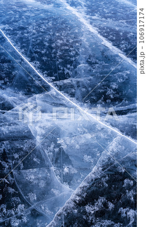 Transparent dark blue ice of frozen Baikal lake with white cracks pattern. Beautiful winter nature background with copy space. Transparent dark blue ice of frozen Baikal lake with white cracks pattern. Beautiful winter nature background with copy space. 106917174